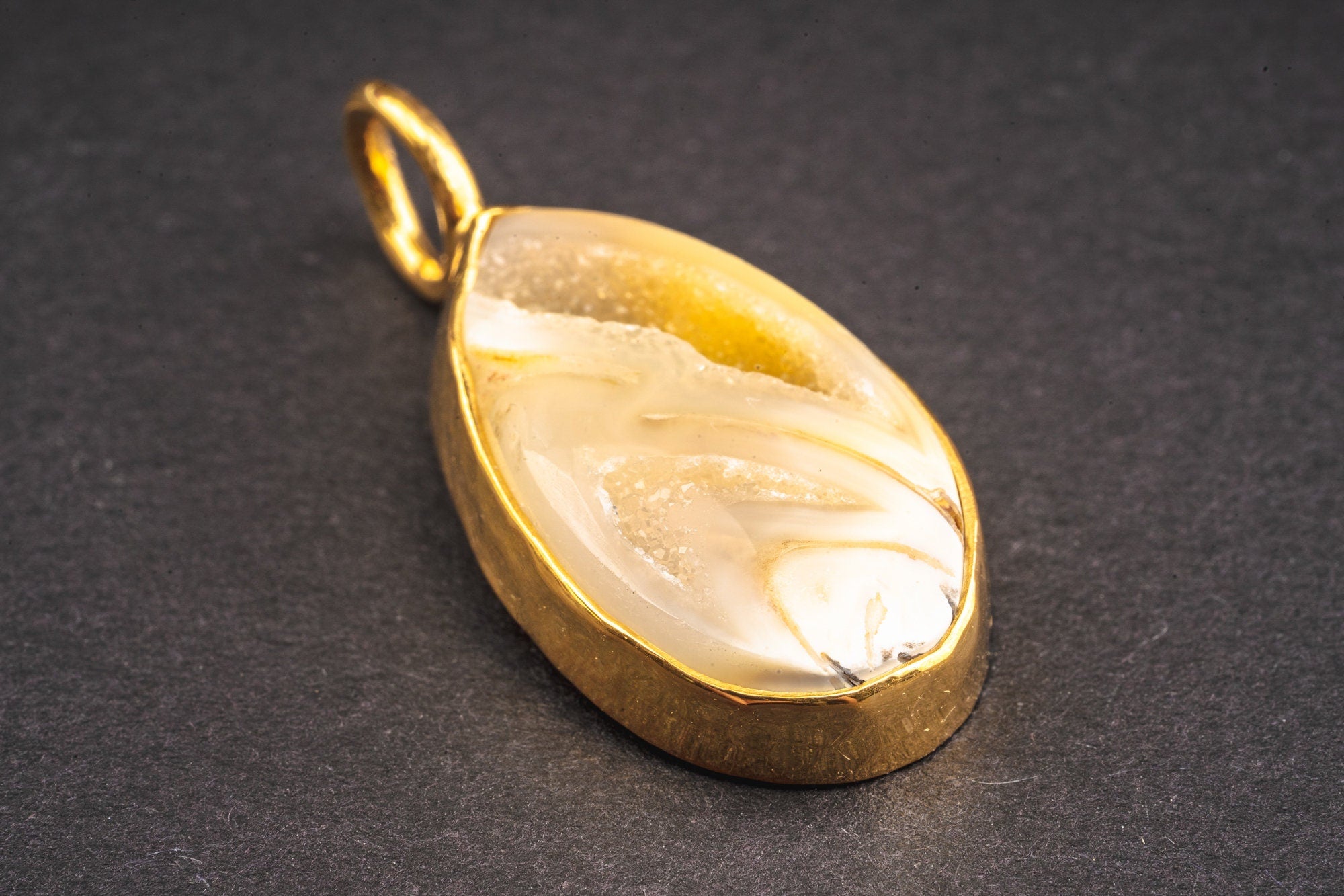 Gold-plated sterling silver seashell pendant shown on dark background with hammered bezel and ocean talisman design.