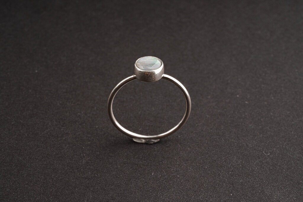 Lightning Ridge Black Opal sterling silver ring shown on a dark background, with rough opal face and delicate round band.