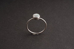 Lightning Ridge Black Opal sterling silver ring shown on a dark background, with rough opal face and delicate round band.