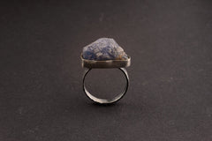 Raw Tanzanite sterling silver ring shown upright on a dark background, with blue-violet crystal texture and bezel setting.