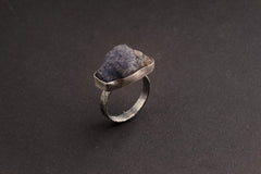 Side view of handmade raw Tanzanite ring showing the raised blue-violet stone, bezel setting, and fine silver band.