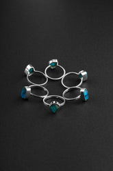 Raw Blue Apatite Ring collection shown on black background with handmade sterling silver bands and bright blue crystals.