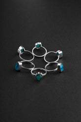 Raw Blue Apatite Ring collection shown on black background with handmade sterling silver bands and bright blue crystals.