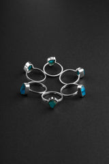 Raw Blue Apatite Ring collection shown on black background with handmade sterling silver bands and bright blue crystals.