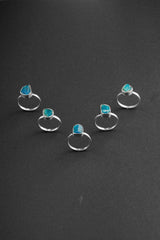Raw Blue Apatite Rings shown on black background with bright blue stones and handmade sterling silver settings.