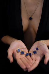 Model holding a blue gemstone necklace with a gold-plated Lapis Lazuli pendant and matching deep blue stone details.
