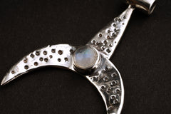 Close-up of oxidized sterling silver crescent pendant showing hammered texture and soft Blue Moonstone glow.