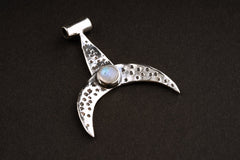 Crescent moon whale fin pendant shown on dark background with textured sterling silver and Blue Moonstone.