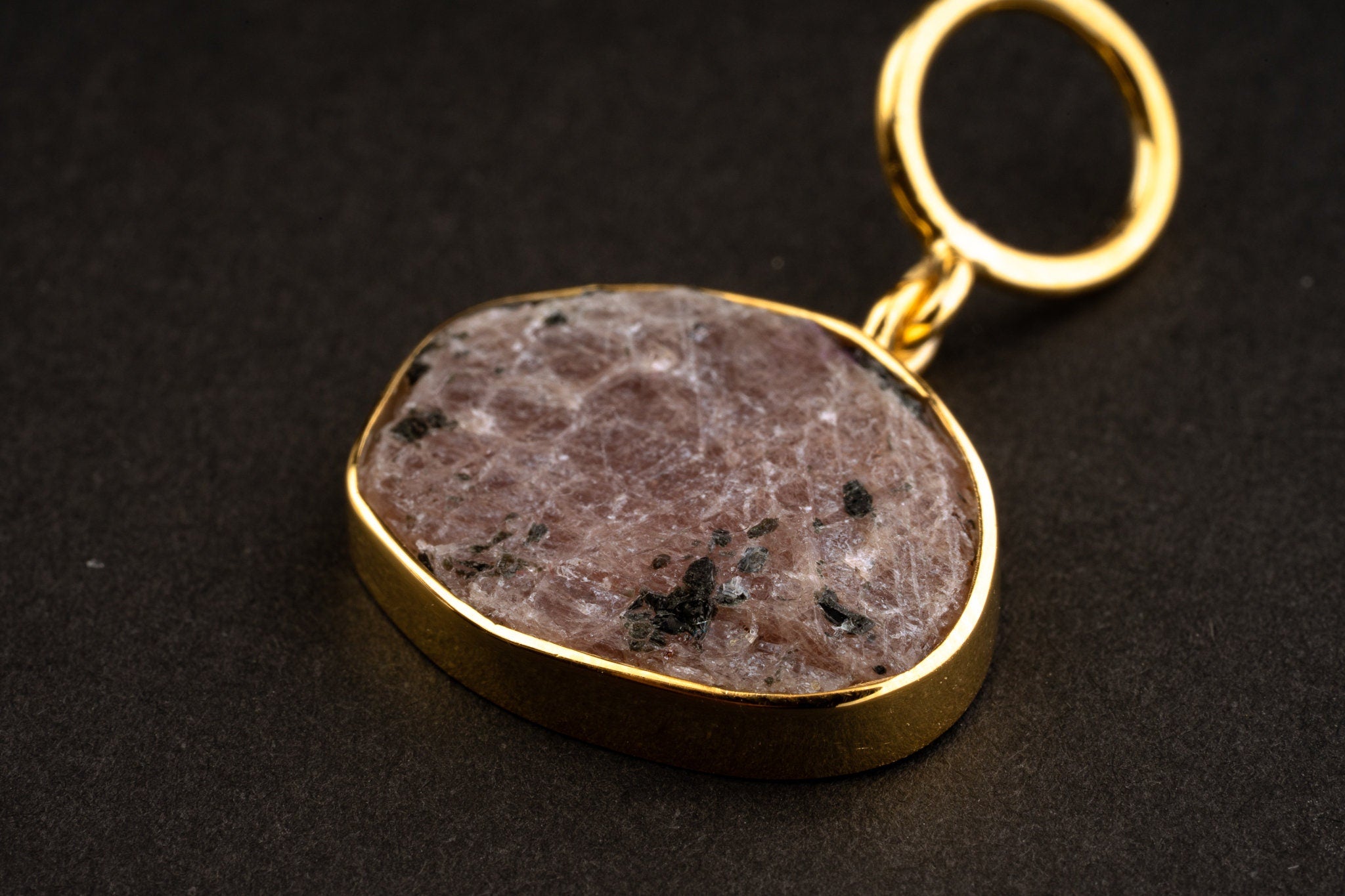 Close-up of raw Ruby record keeper pendant with gold-plated silver cap, wide bail, mica inclusions, and earthy red mineral texture.