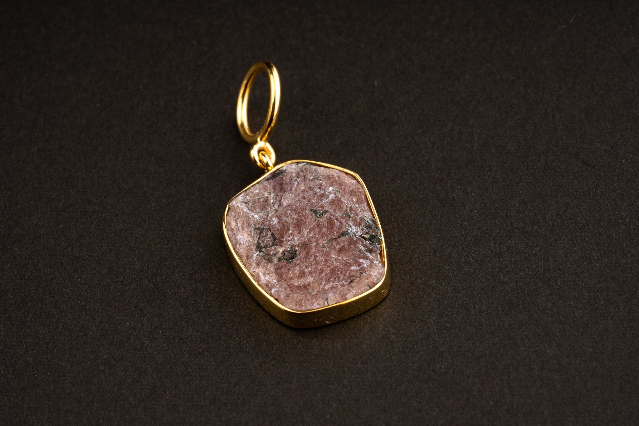 Raw Indian Ruby record keeper pendant with mica inclusions and 16k gold-plated sterling silver setting on a dark background.