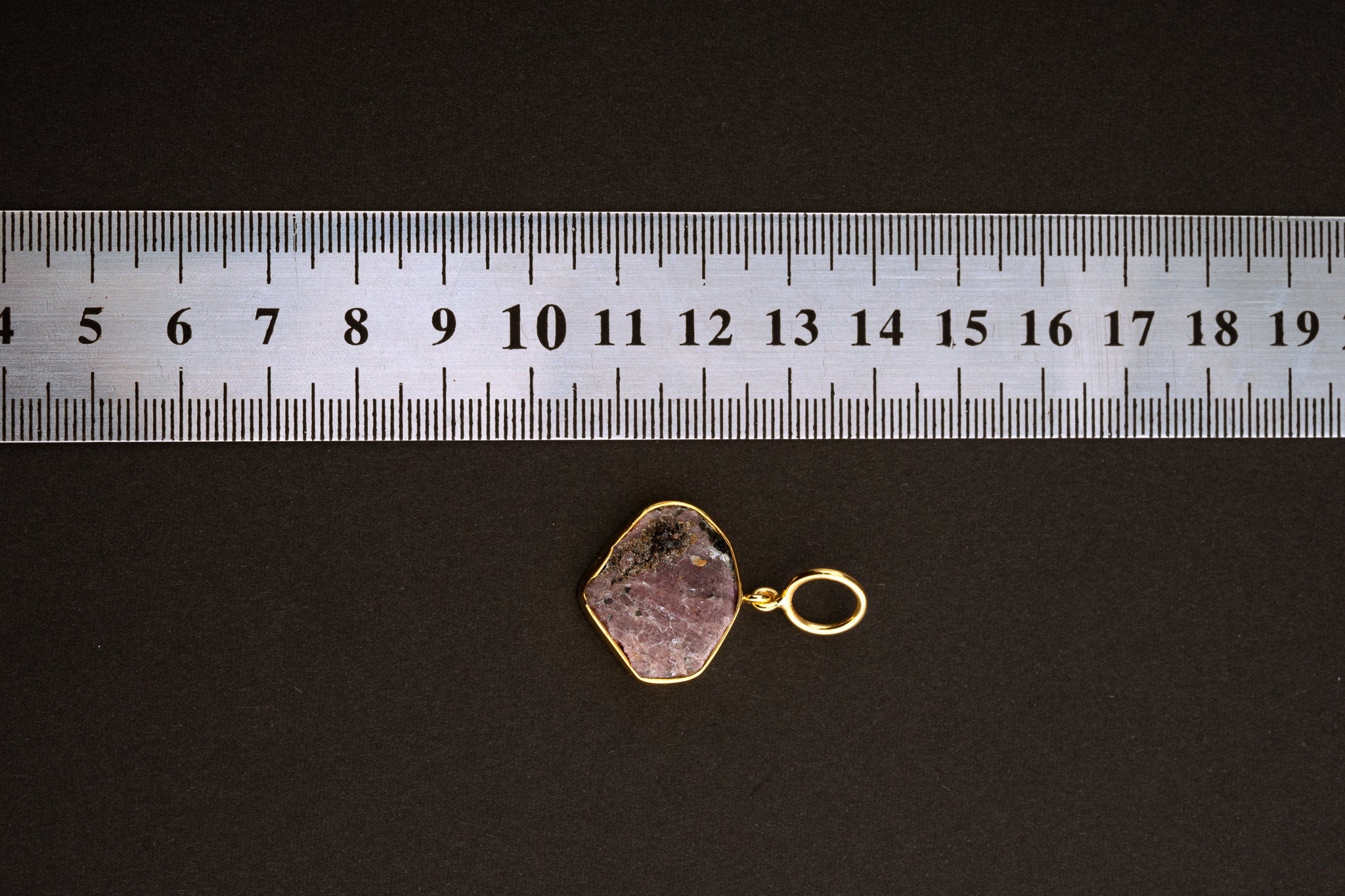 Raw Indian Ruby pendant shown beside a ruler for scale, measuring approximately 2.7 to 3 cm total length including bail.