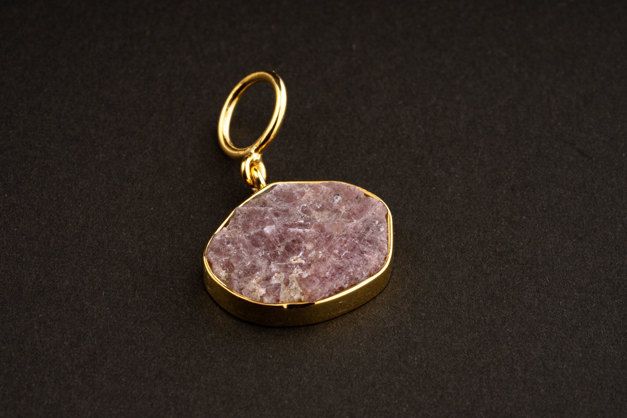 Raw Indian Ruby pendant with mica inclusions and 16k gold-plated sterling silver setting, shown on a dark background.