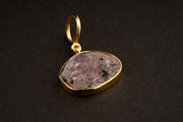 Raw Indian Ruby pendant with mica inclusions and 16k gold-plated sterling silver setting, shown on a dark background.