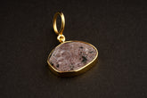 Raw Indian Ruby pendant with mica inclusions and 16k gold-plated sterling silver setting, shown on a dark background.
