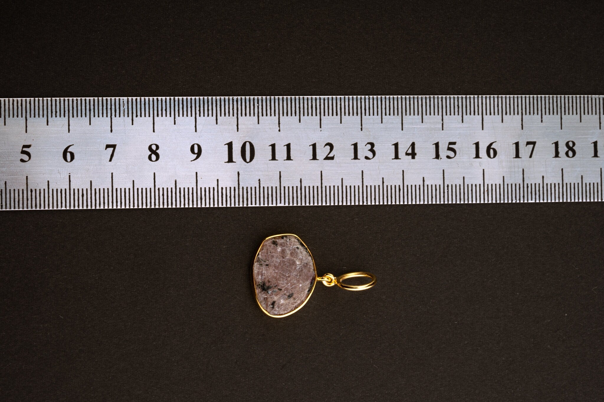 Raw Indian Ruby pendant shown beside a ruler for scale, measuring approximately 2.5 cm total length including bail.