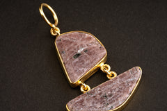 Raw Ruby record keeper double pendant on a dark background, showing linked two-stone construction and warm gold-plated setting.