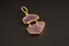 Raw Ruby record keeper double pendant on a dark background, showing linked two-stone construction and warm gold-plated setting.
