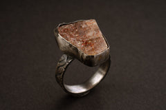 Handmade 925 sterling silver Sunstone ring shown on a dark background, with warm orange gemstone and sturdy silver band.