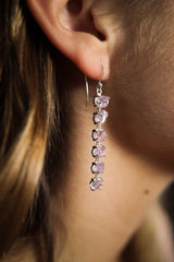 Raw Amethyst dangle earring shown worn on the ear, with deep purple stones and fine sterling silver hook.