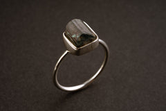 Watermelon Tourmaline sterling silver stack ring shown on a dark background, with rough crystal and fine silver band.