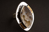 Ammonite fossil adjustable ring in hammered 925 sterling silver with brass accents, shown close-up on a dark background.