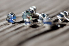 Australian creek tumbled Sapphire stud earrings shown close up, with organic blue stones and sterling silver claw settings.