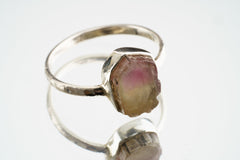 Pink Tourmaline Sterling Silver Ring shown on white background with polished silver band and raw pink gemstone.