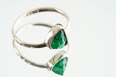Emerald sterling silver ring shown on a light background, with a vivid green gemstone and handmade silver band.