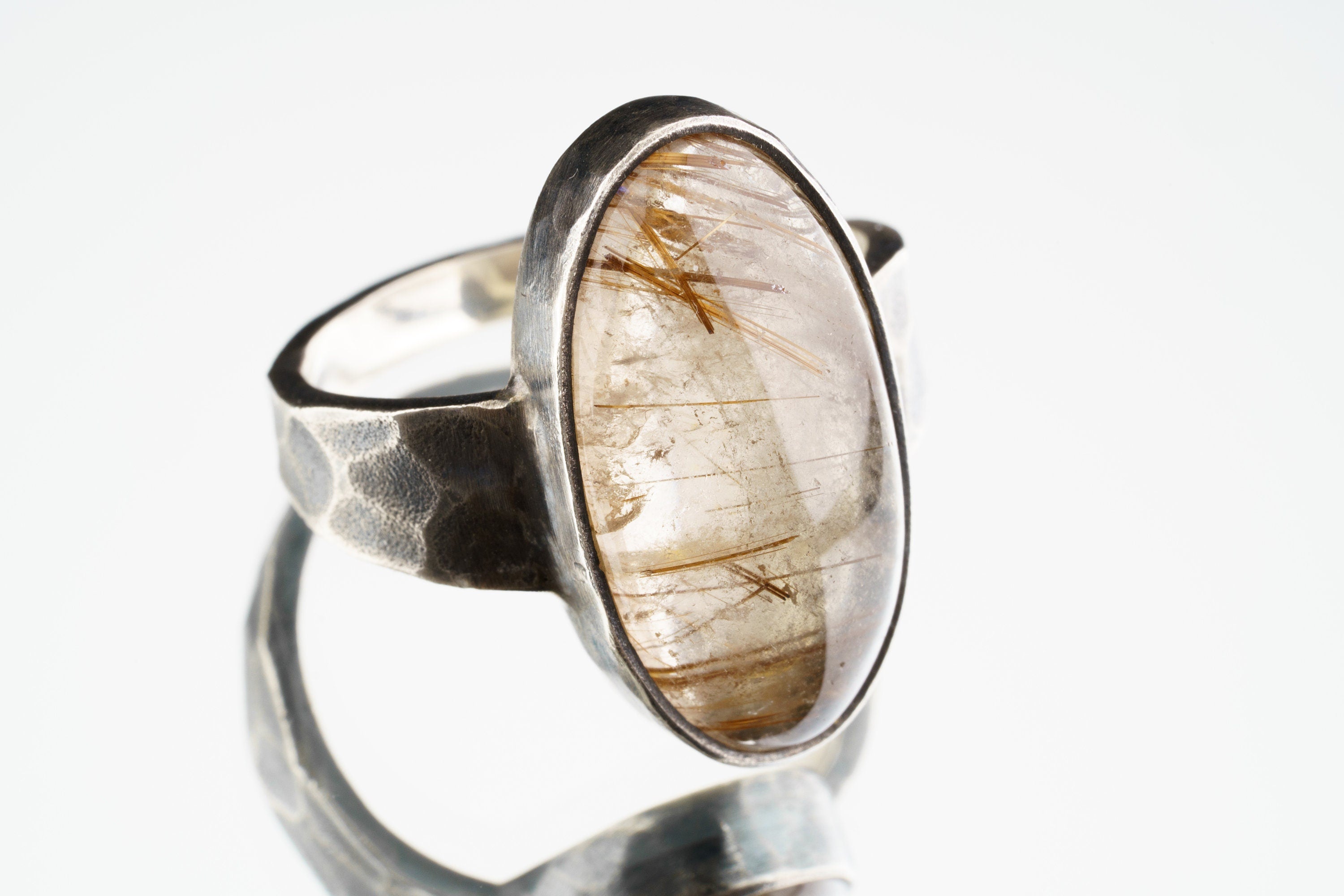 Rutilated Quartz ring in oxidized 925 sterling silver with hammered texture, open-back bezel, and visible rutile strands.