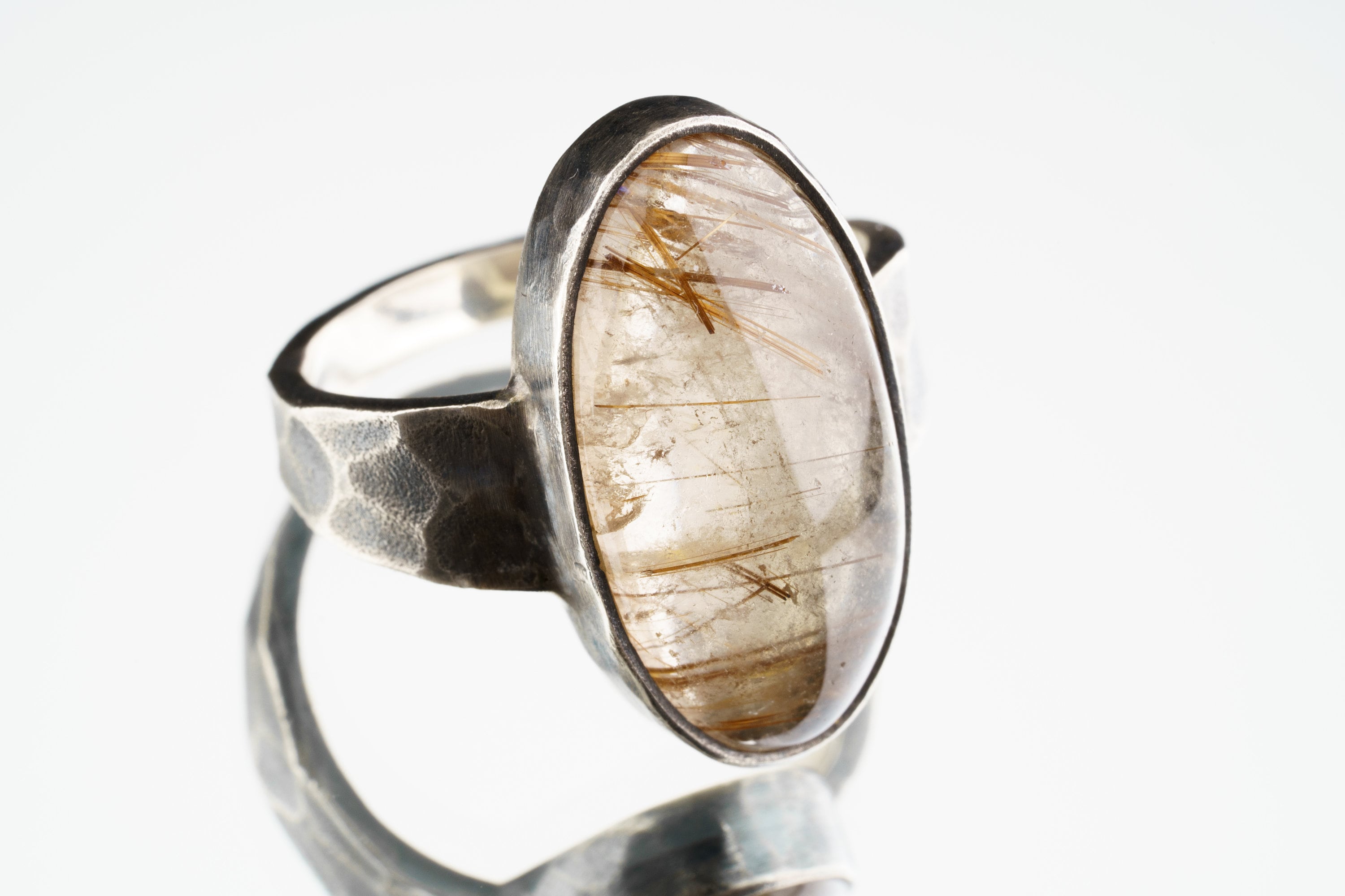 Rutilated Quartz ring in oxidized 925 sterling silver with hammered texture, open-back bezel, and visible rutile strands.