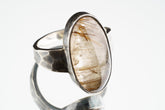 Rutilated Quartz ring in oxidized 925 sterling silver with hammered texture, open-back bezel, and visible rutile strands.