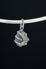 Green Tourmaline pendant shown worn on black background with compact oxidized silver claw setting.