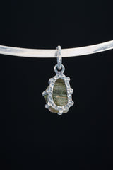 Green Tourmaline Claw Pendant on black background with handmade oxidized sterling silver frame.