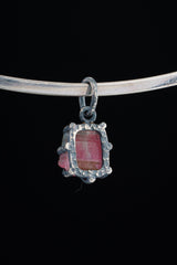 Pink Tourmaline Rubellite pendant shown worn on black background with compact oxidized silver claw setting.