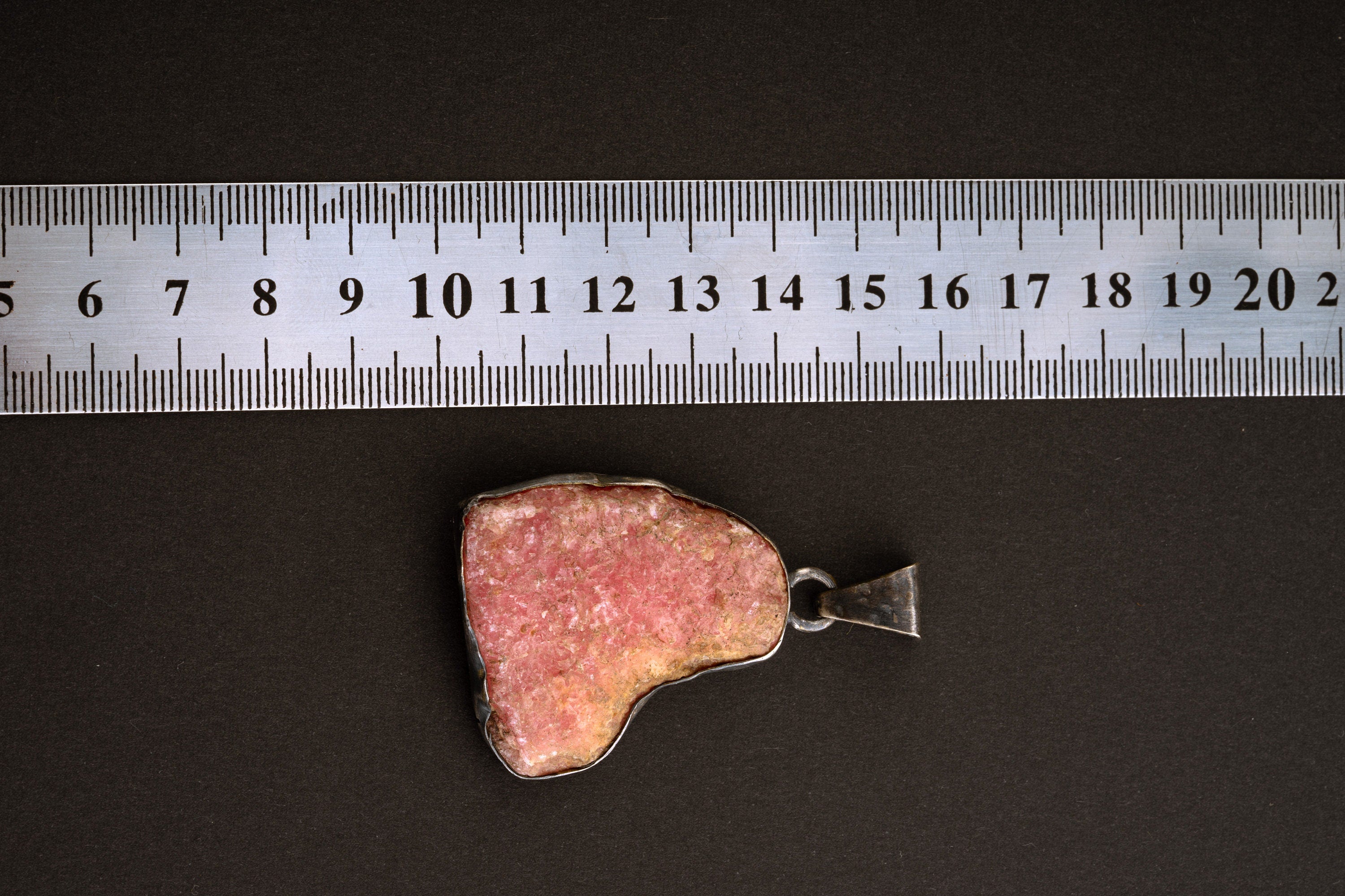 Rhodochrosite sterling silver pendant shown beside a ruler for scale with organic pink stone shape.