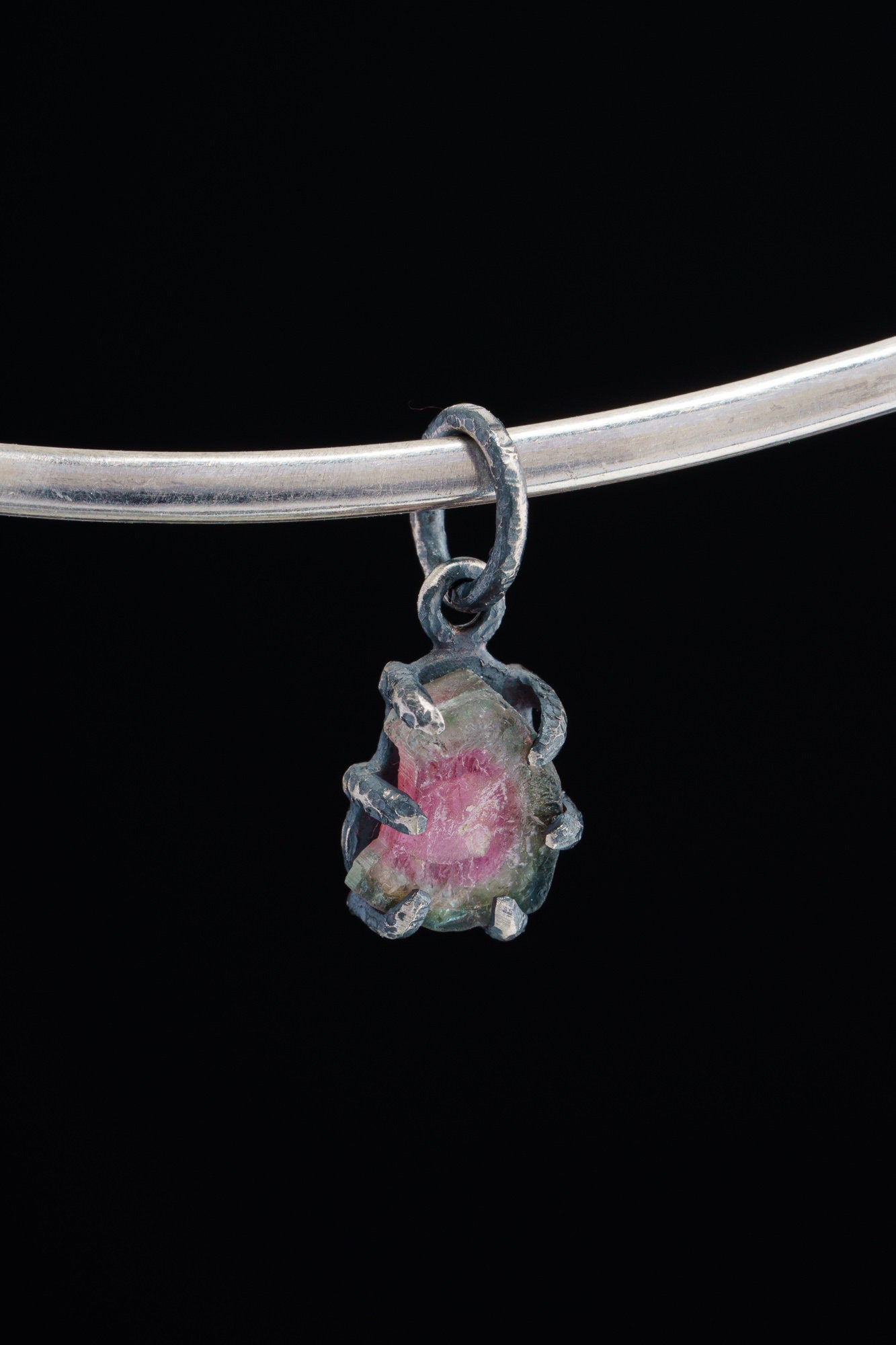 Watermelon Tourmaline Claw Pendant on black background with oxidized sterling silver and natural pink-green crystal.