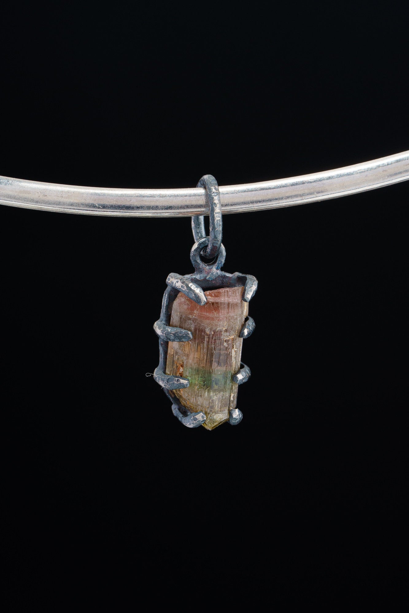 Watermelon Tourmaline Claw Pendant on black background with oxidized sterling silver setting and pink-green gemstone.