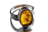 Amber ring in oxidized 925 sterling silver with hammered texture, open-back bezel, and golden honey organic gemstone.