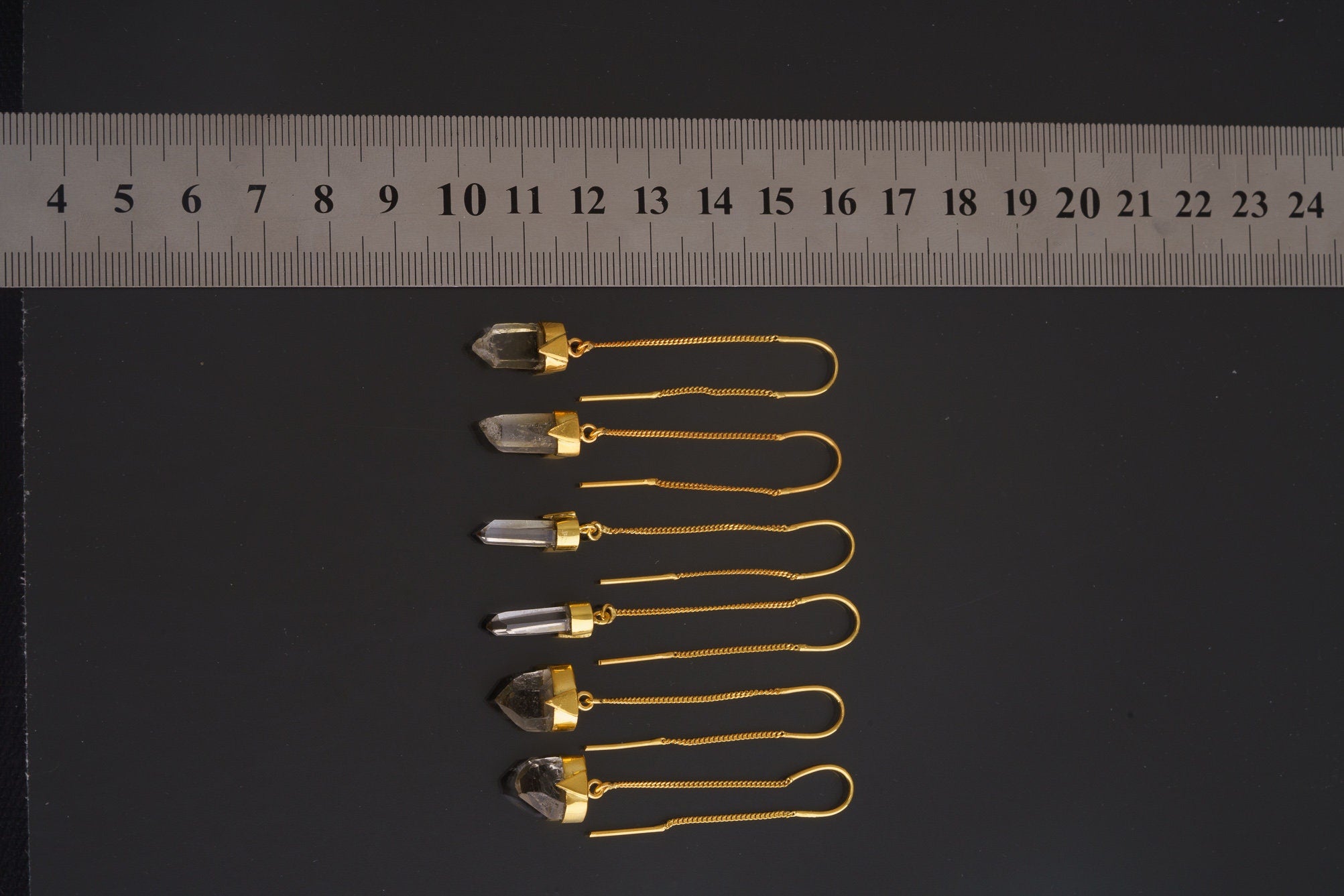 Himalayan Quartz gold-plated dangle earring collection shown beside a ruler with clear crystal points.