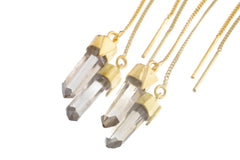 close-up of Himalayan Quartz gold-plated dangle earrings shown with clear crystal points and fine hook fittings.