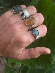 Amber ring shown worn with other rings on the hand, highlighting its golden glow and oxidized handmade silver setting.