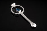 Blue Apatite sterling silver hammered spoon pendant shown on dark background with vivid blue gemstone setting.