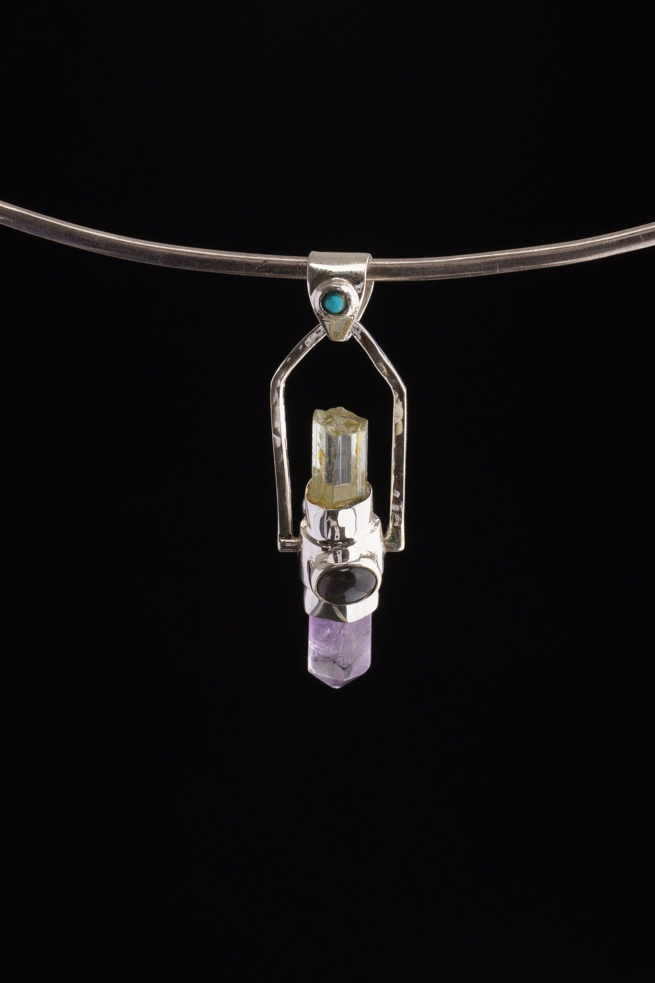 Two Sided Gemstone Spinner Pendant shown on black background with high-polish sterling silver and mixed blue gemstone details.