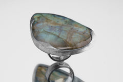 Side view of XXL Labradorite adjustable ring showing thick silver waved bezel and raised stone setting.