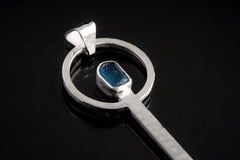 Close-up of Blue Apatite spoon pendant showing hammered sterling silver texture and bright blue gemstone.