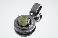 Peridot pendant shown worn on the chest, with bright green stone, oxidized silver setting, and black cotton cord.