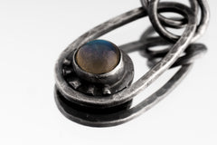 Close-up of round Labradorite cabochon in a polished 925 sterling silver Cosmic Ray pendant with handmade ray accents.
