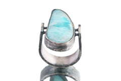 Front view of Larimar oxidized silver ring showing pale blue pectolite stone and rugged hammered band texture.