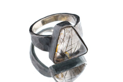 Rutilated Quartz ring in oxidized 925 sterling silver with hammered texture, open-back bezel, and visible rutile strands.