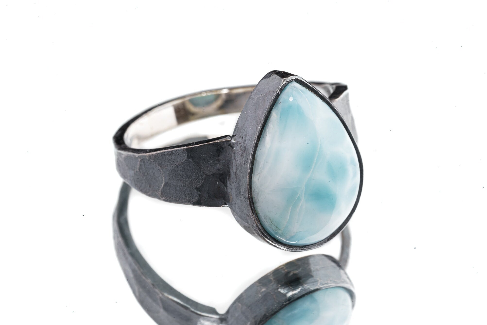 Larimar ring in oxidized 925 sterling silver with hammered texture, open-back bezel, and soft ocean-blue stone.